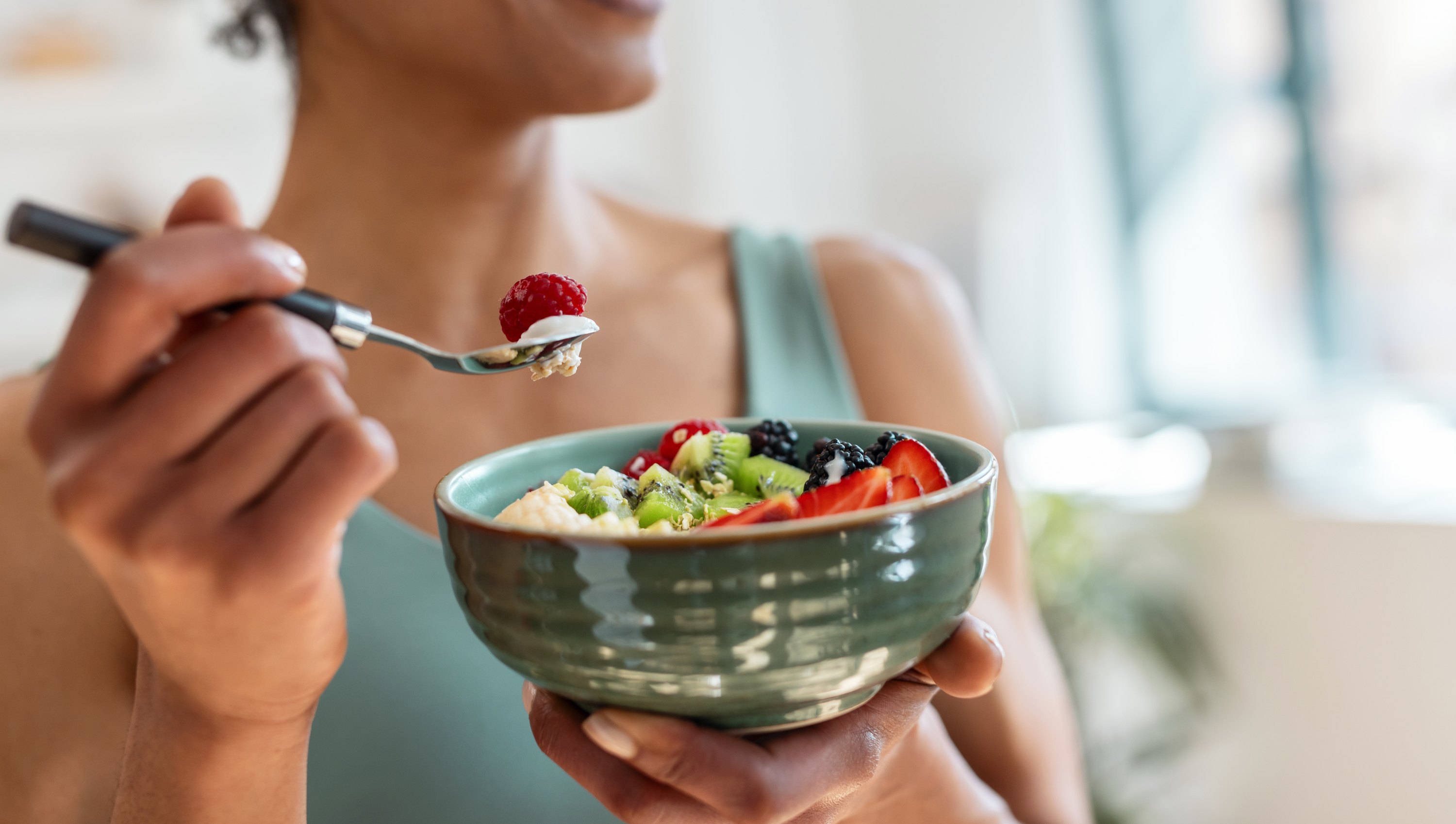 a woman eating from a bowl of fruit