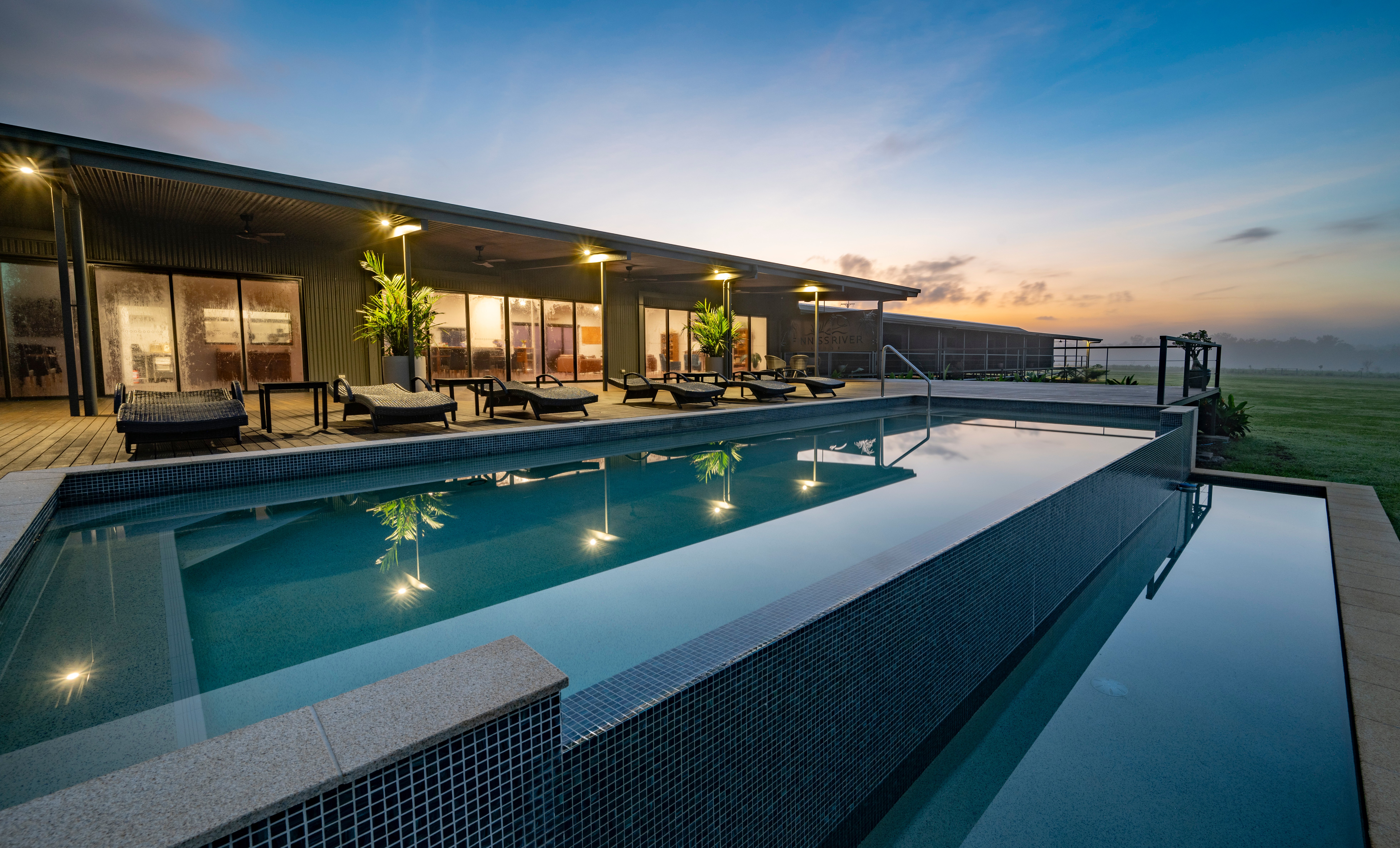 Finniss River Lodge with an infinity pool and lounge chairs at dusk.
