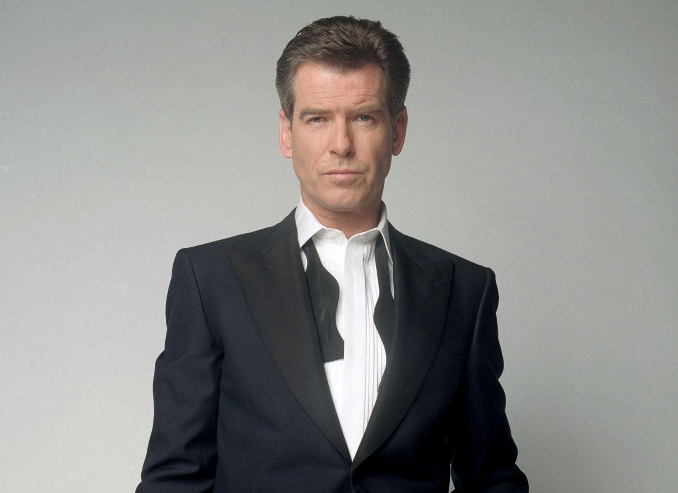 Pierce Brosnan as James Bond in "Die Another Day" wearing a tuxedo with an undone bow tie, holding a pistol.
