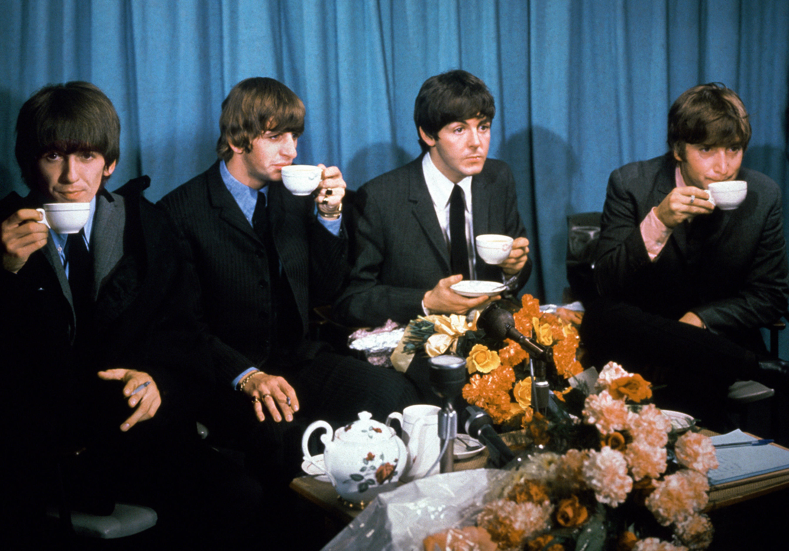 Publicity photo of The Beatles: George Harrison, Ringo Starr, Paul McCartney, and John Lennon drinking tea.