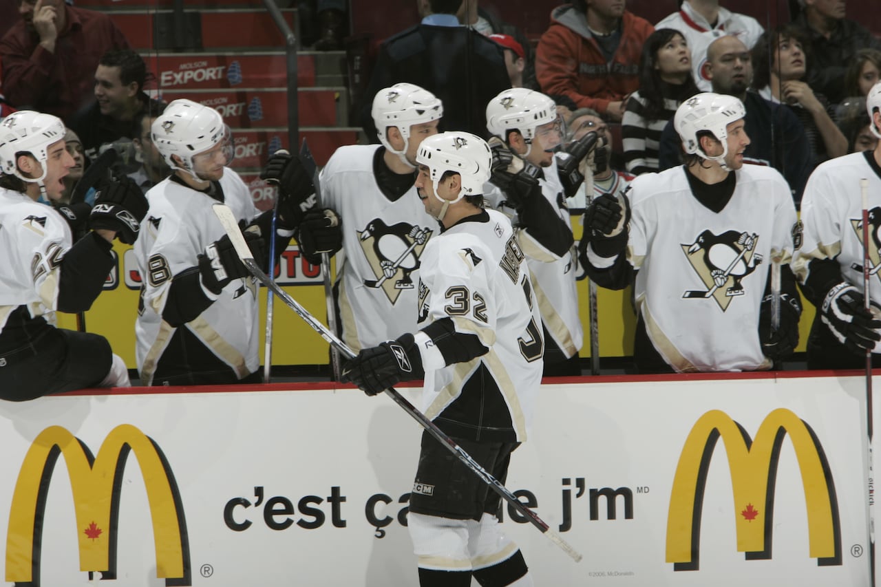 A hockey player is shown celebrating a goal with his teammates at their bench.