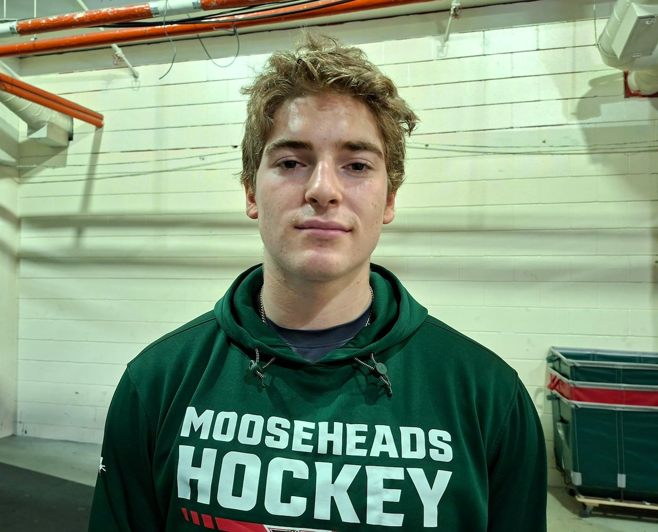 A junior hockey player poses for a photo inside the rink.