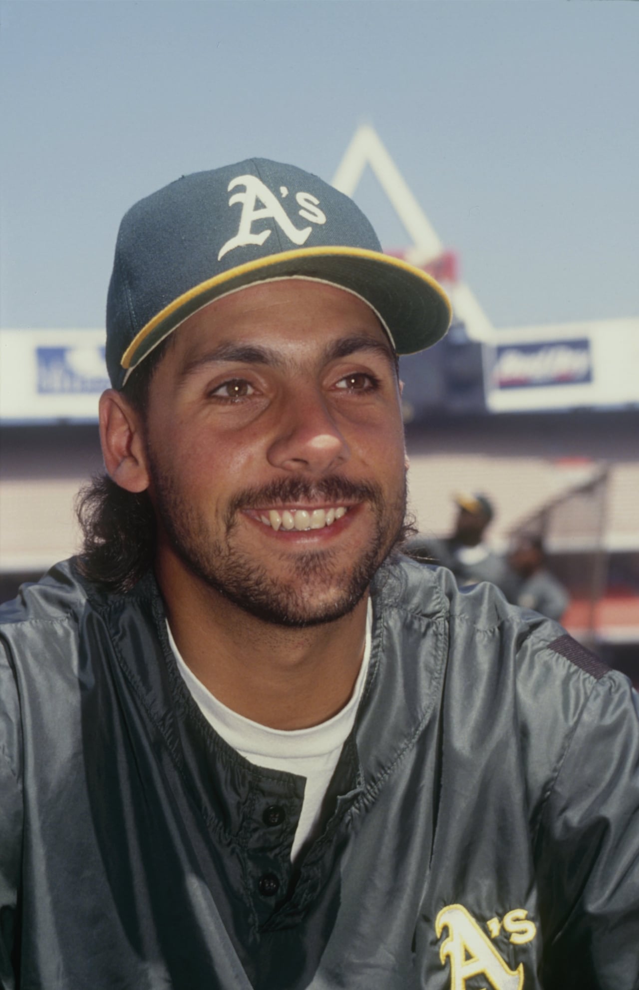 A baseball player smiles while looking away from the camera.