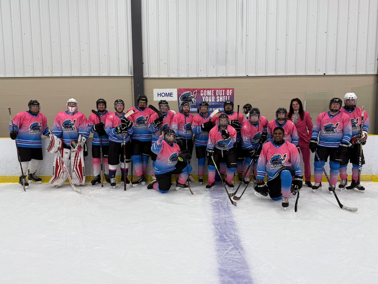 A group of hockey players wearing pink uniforms pose for a photo on the ice.