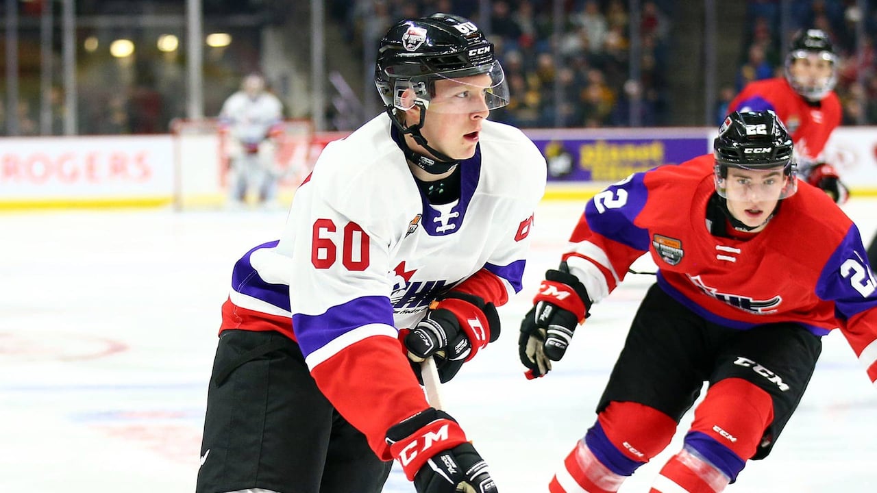 A closeup of two hockey players on rival teams on the ice during a game.