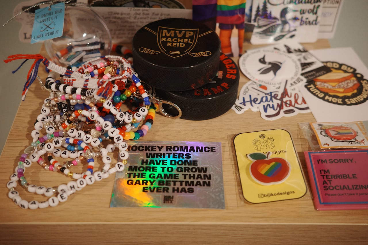 A series of trinkets sent to author Rachel Reid. Friendship bracelets, a hockey puck, and stickers can be seen.
