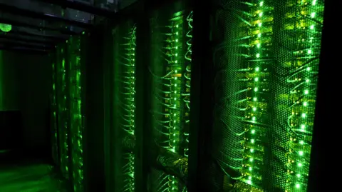Reuters A bank of glowing green computer cables shine brightly against a deep black background in what is an unidentified data centre storage facility 