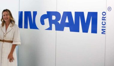 A photograph of Ingram Micro's Hope McGarry standing in front of the Ingram Micro logo.