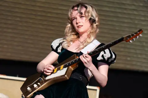 Getty Images Emily Roberts of The Last Dinner Party plays guitar at the 2024 Glastonbury Festival