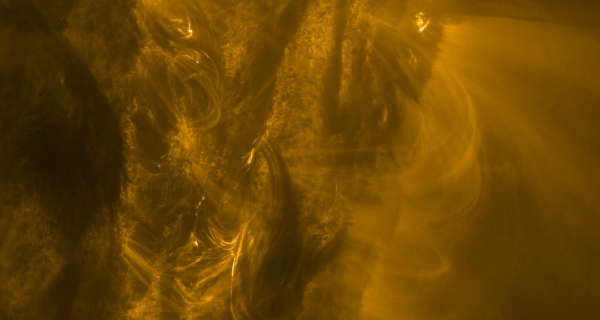 A close up of the sun showing golden light and energy spewing from its side