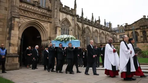 EPA Pallbearers carry the coffin which is adorned with white flowers after the funeral service at Manchester Cathedral