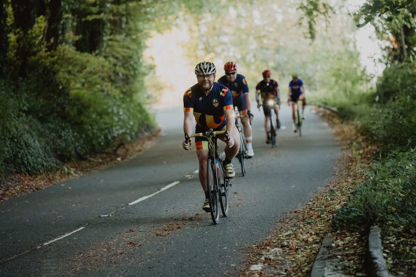 Group of cyclists go up a hill, autumn leaves around them