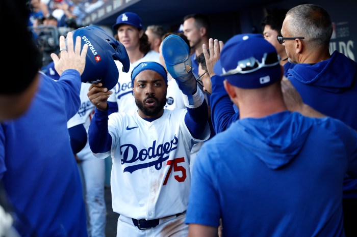 Justin Dean of the Los Angeles Dodgers is congratulated in the dugout after scoring a run