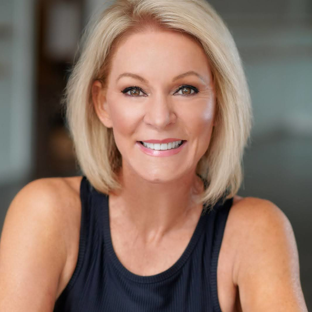 Head and shoulders of smiling woman with blond hair wearing a black vest top
