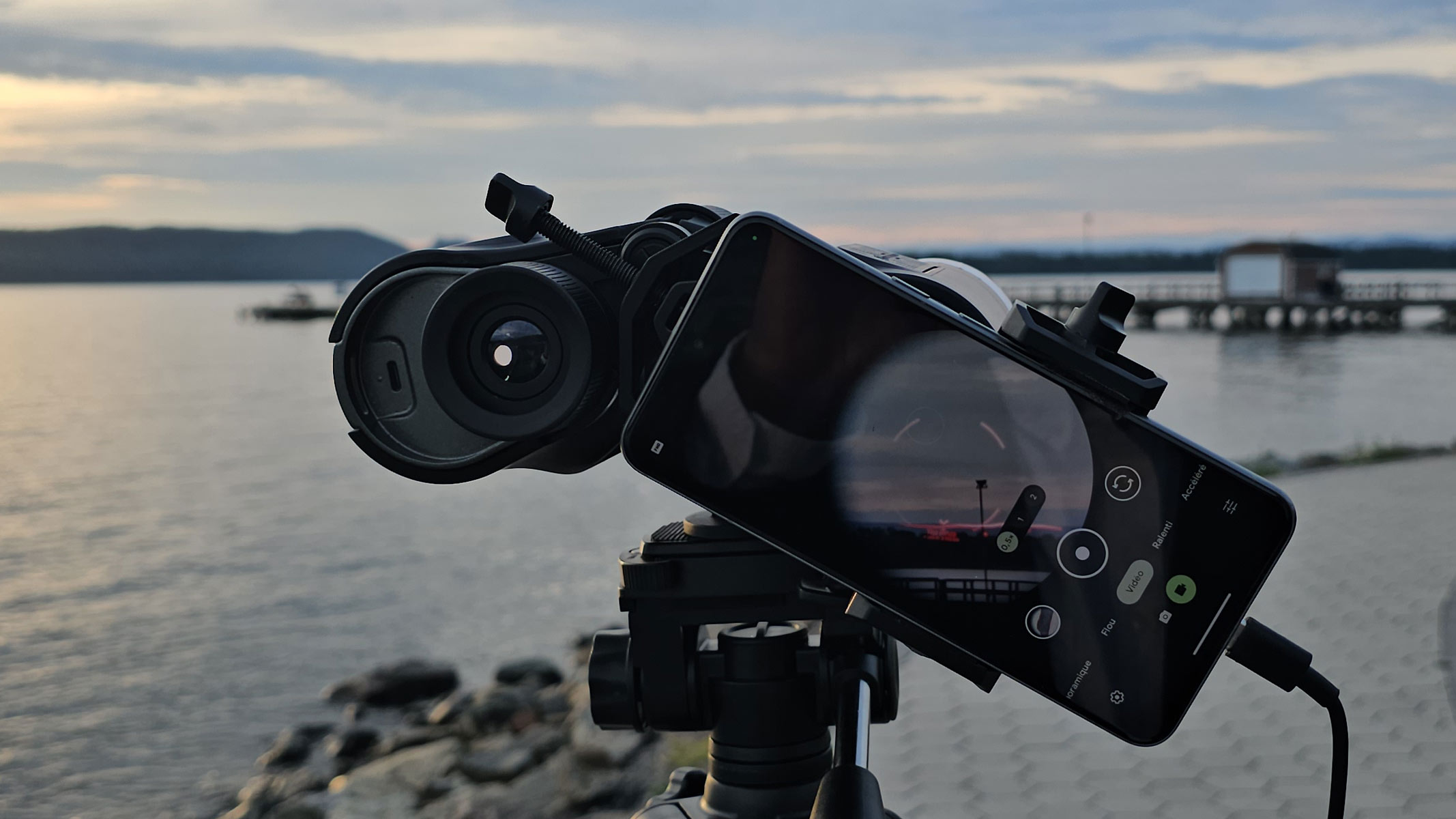 A smartphone showing the view through the Unistellar Envision binoculars with a red AR overlay of the landscape with a lake in the background.