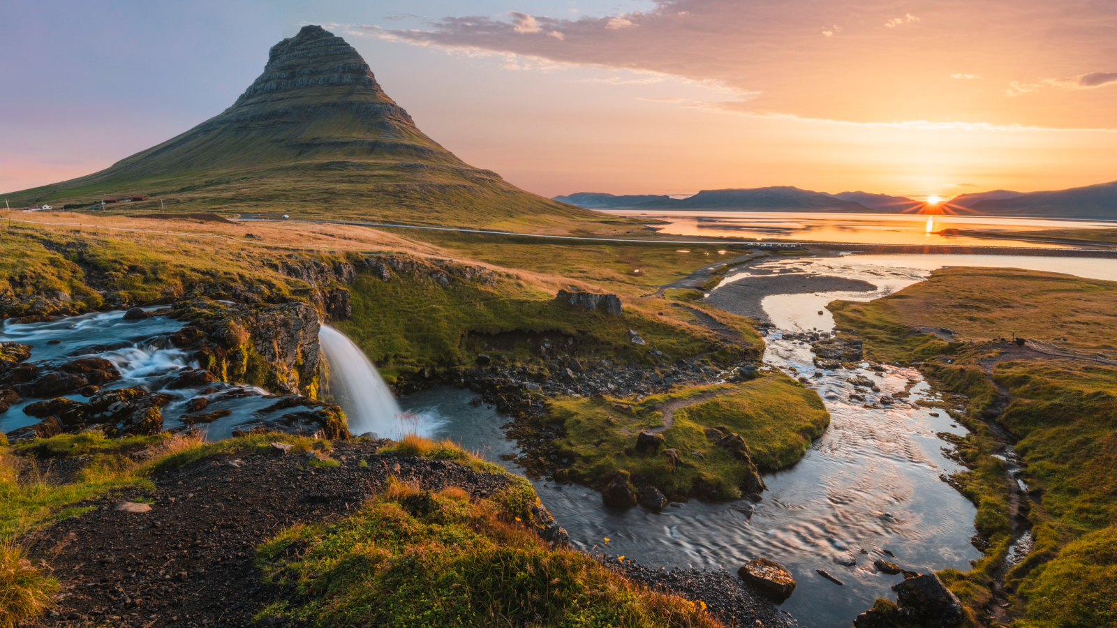 Mount Kirkjufell and Kirkjufellsfoss waterfall at sunrise in Iceland.