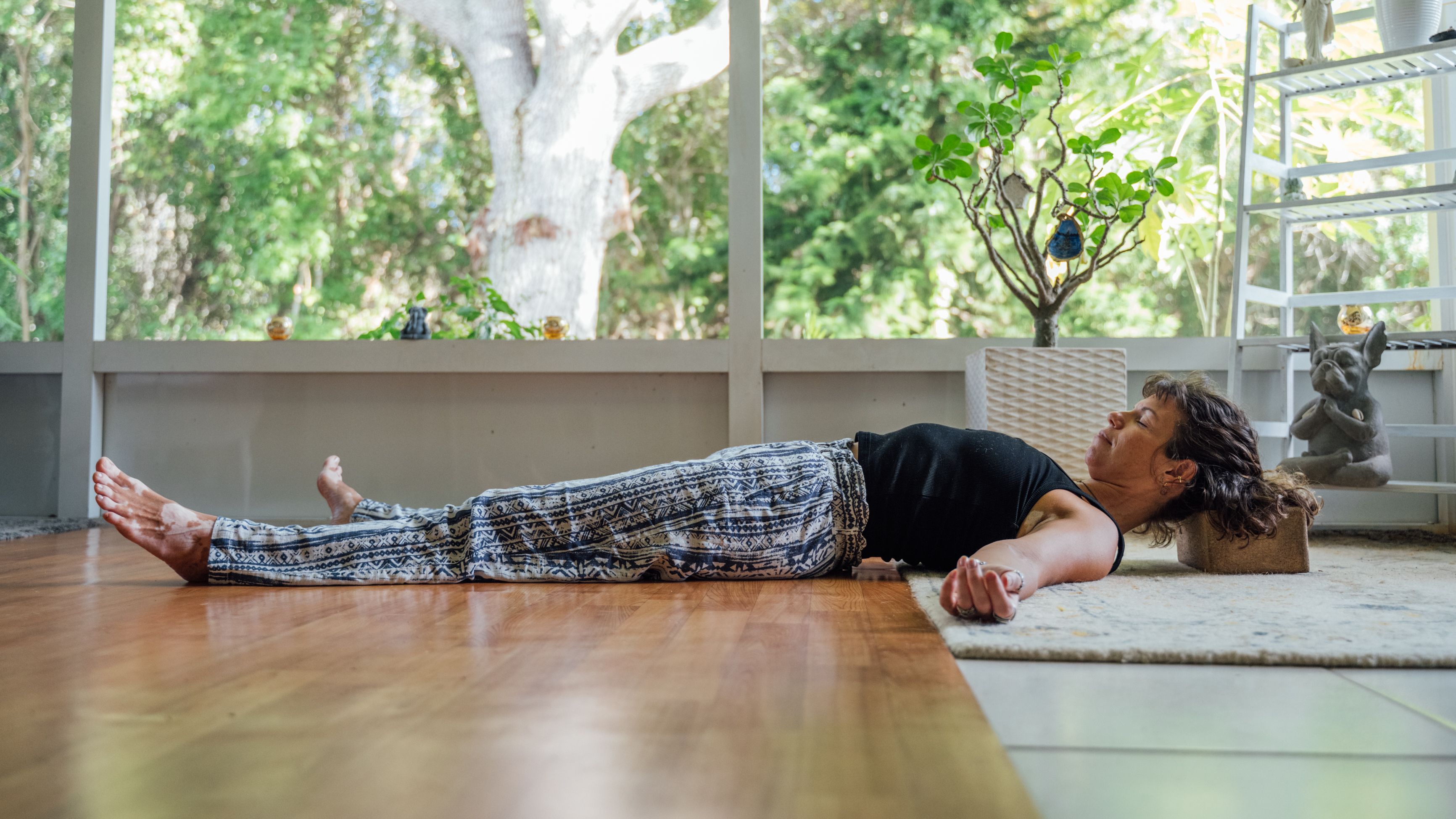 Woman lying on her back with the back of her head resting on a yoga block