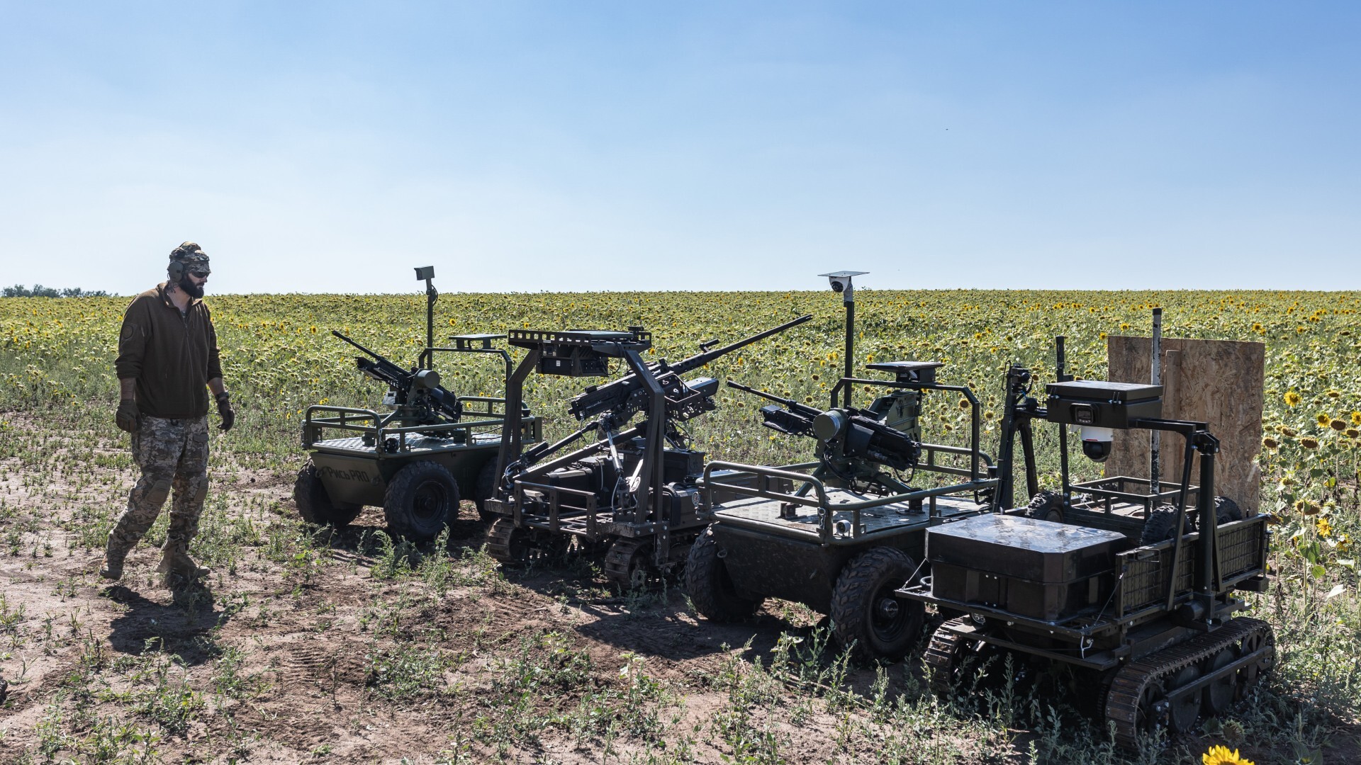 Ukrainian soldiers using tractors in the middle of a field with sunflowers.