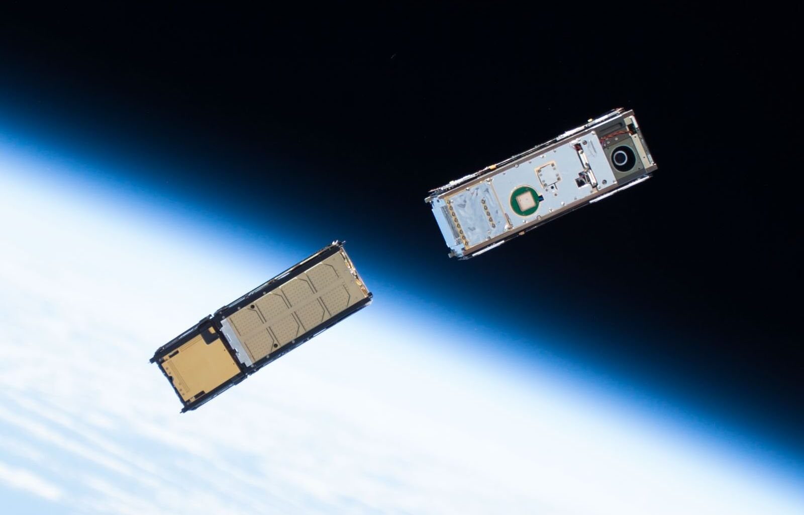 Two CubeSats orbiting around Earth after being deployed from the ISS Kibō module's Small Satellite Orbital Deployer. The environment for satellites in low Earth orbit makes them susceptible to atmospheric drag and to corrosion (Credit : NASA)