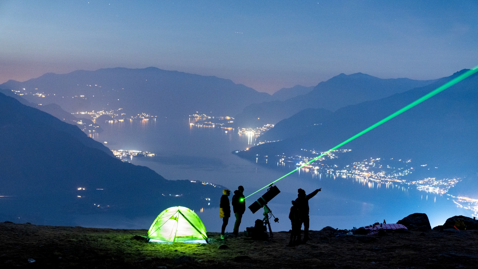 Photo of a group of stargazers next to a telescope in mountians