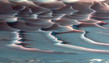 A false color image shows red sand dunes streaking across a blue surface