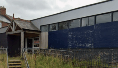 The former Stanley library is an empty one-storey building made of brown bricks and surrounded by overgrown grass.