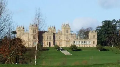Geograph Mentore golf course: A large light brown building sitting behind an area of green grassland. The building has several towers and many windows. Grey steps lead to the entrance.