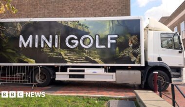 A lorry with mini golf on the side parked outside the townhall