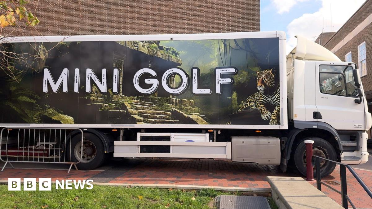 A lorry with mini golf on the side parked outside the townhall