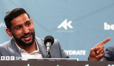 Amir Khan laughs and points his finger speaking at a news conference