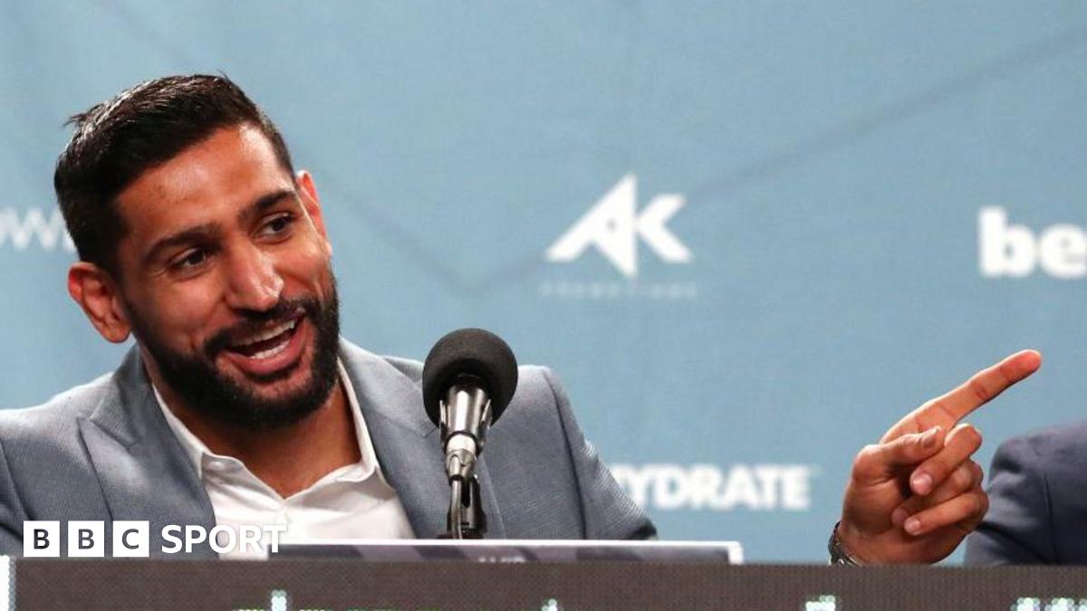 Amir Khan laughs and points his finger speaking at a news conference