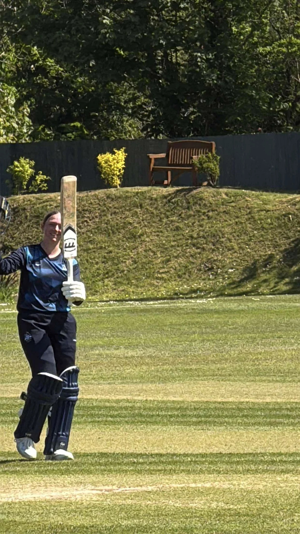 Libby raising her bat after yet another century last season. She is wearing navy cricket kit