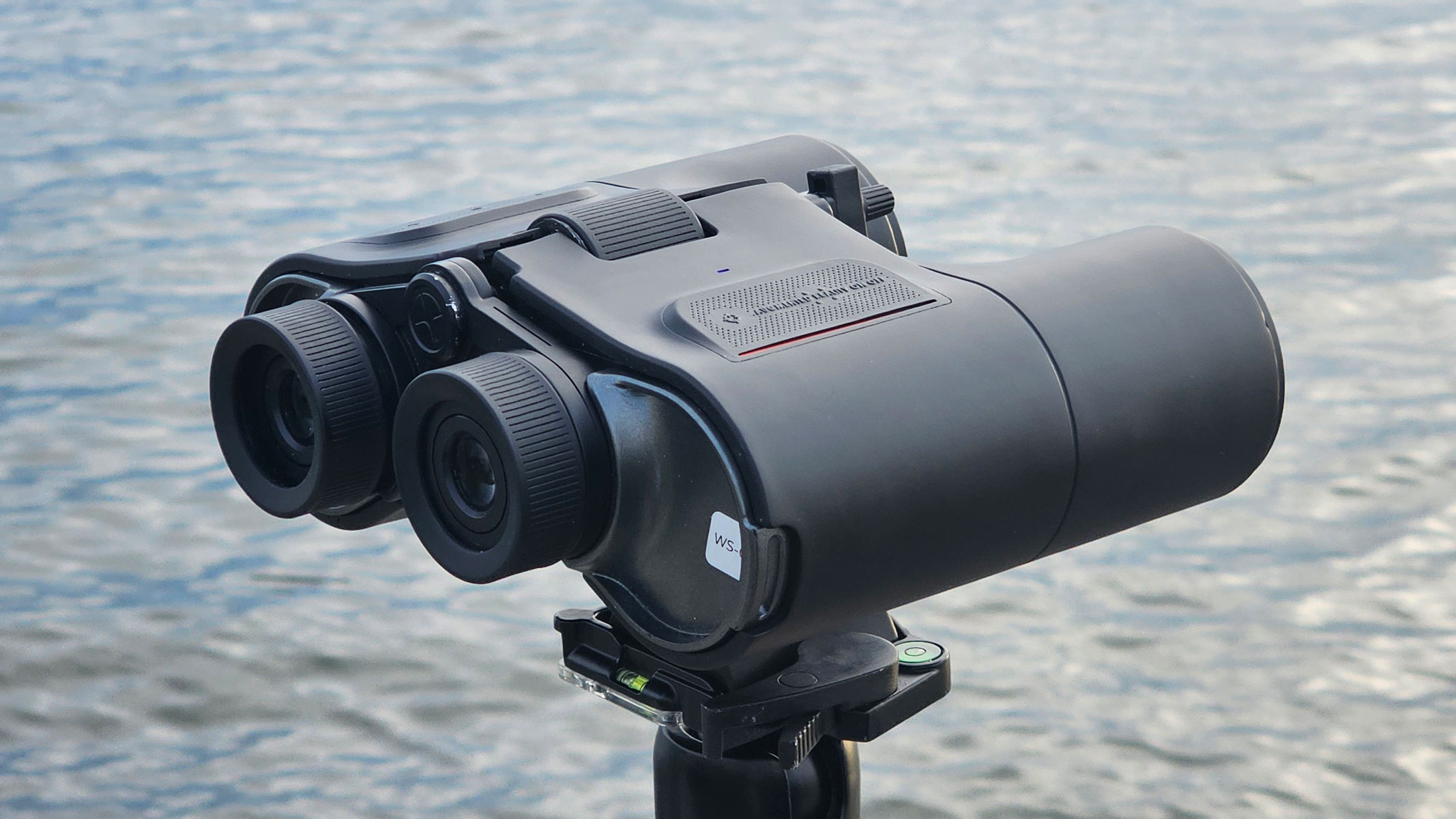 A side back view of the Unistellar Envision smart binoculars with water in the background.