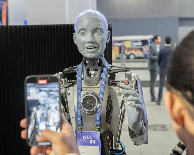 People photograph a human-looking robot.