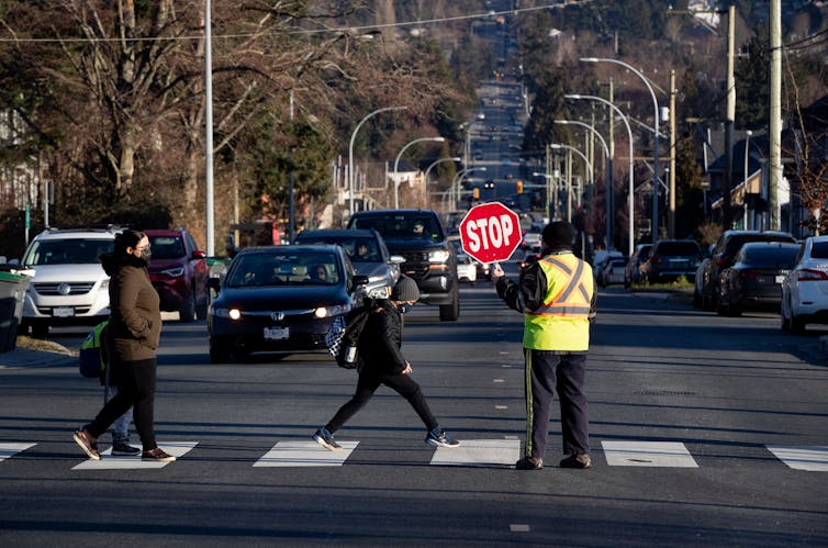 A crossing guard and students in a roadway.