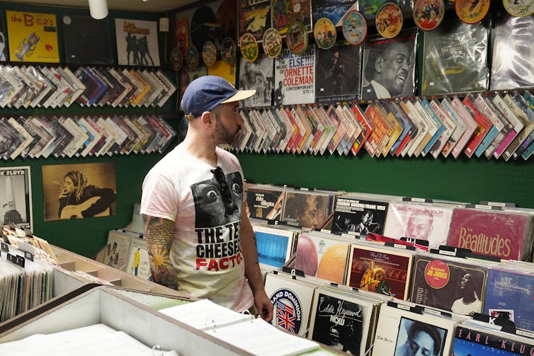A person stands in a record store looking at records on the wall.