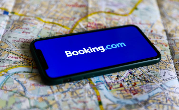Booking.com logo displayed on a phone screen and a map of Krakow