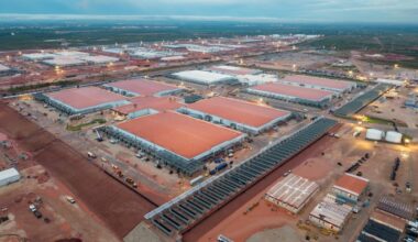 Aerial view of the Stargate AI data center complex in Abilene, Texas, showing large buildings with red roofs, outdoor machinery, and construction vehicles.
