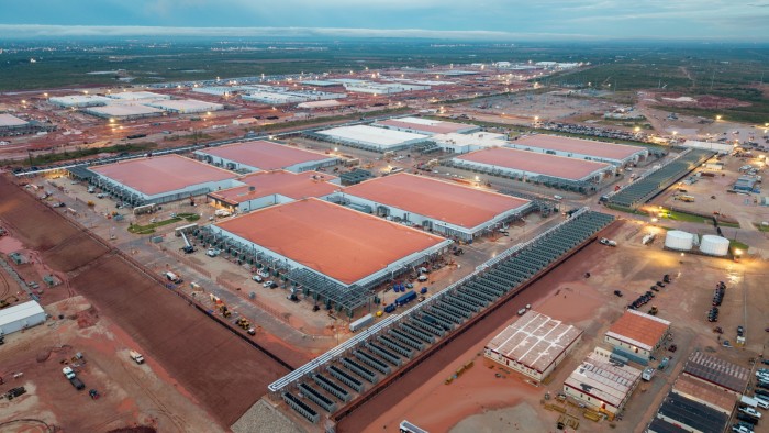 Aerial view of the Stargate AI data center complex in Abilene, Texas, showing large buildings with red roofs, outdoor machinery, and construction vehicles.