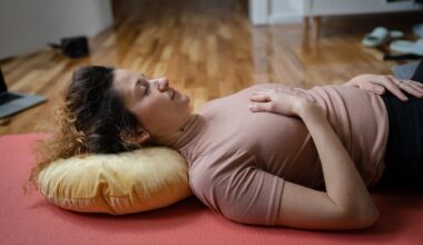 woman lying on her back with a yellow cushion behind her head with one hand on her chest and abdomen.