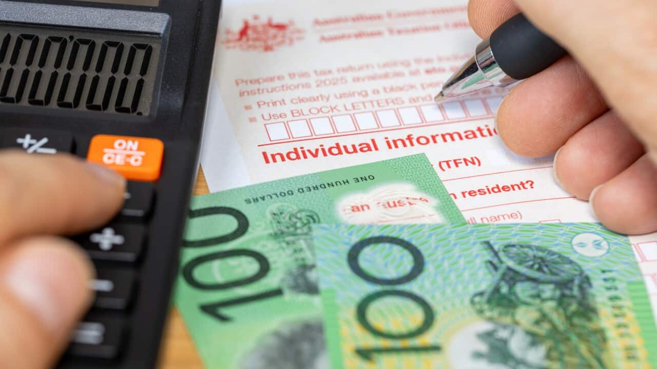 A person filling out a form and using a calculator.