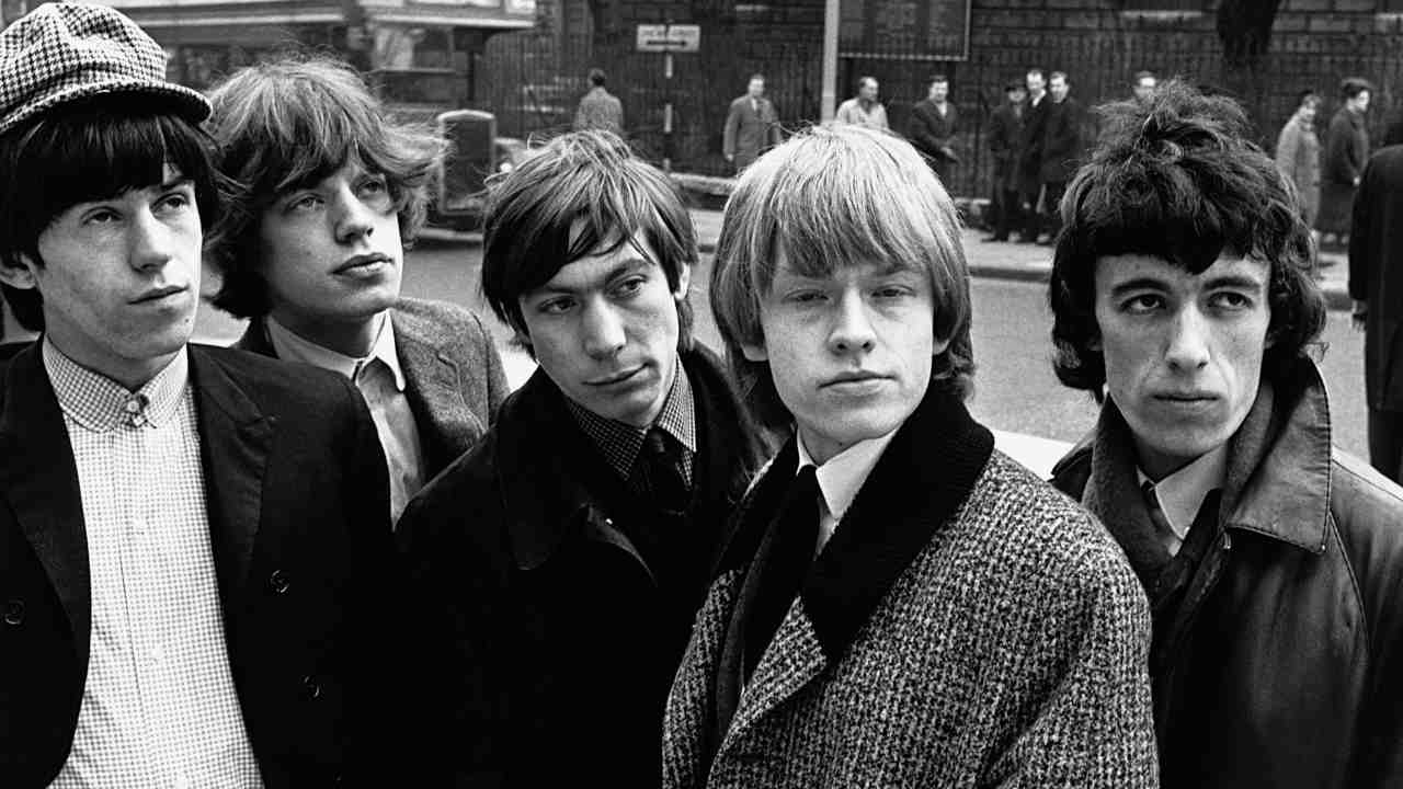 The Rolling Stones posing for a photograph in a busy street in the mid-1960s