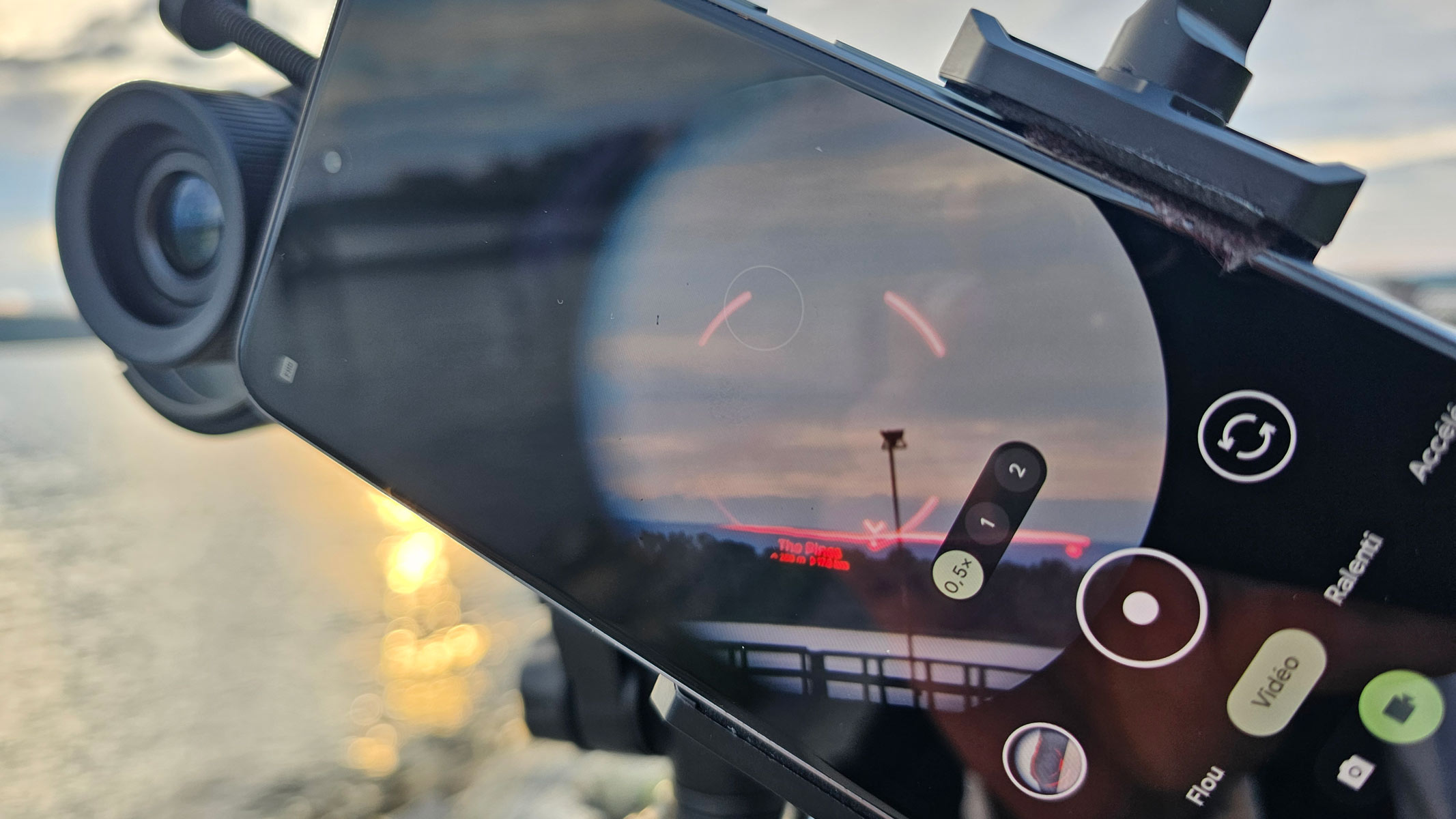 A smartphone showing the view through the Unistellar Envision binoculars with a red AR overlay of a mountain.
