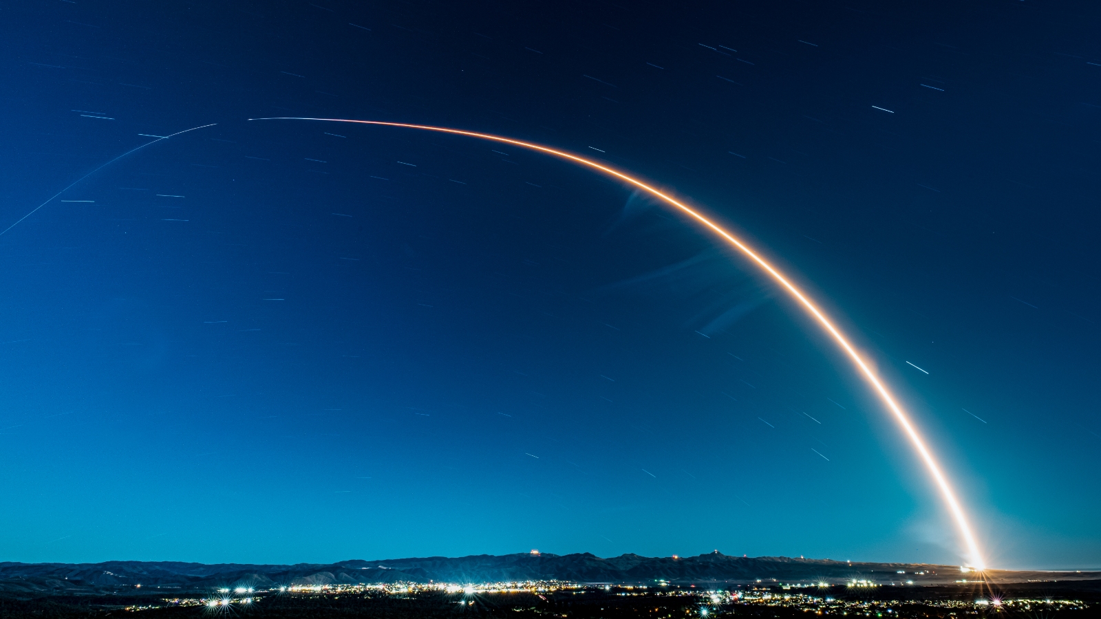 A timelapse photo of a rocket launch showing the streak of light as it takes off