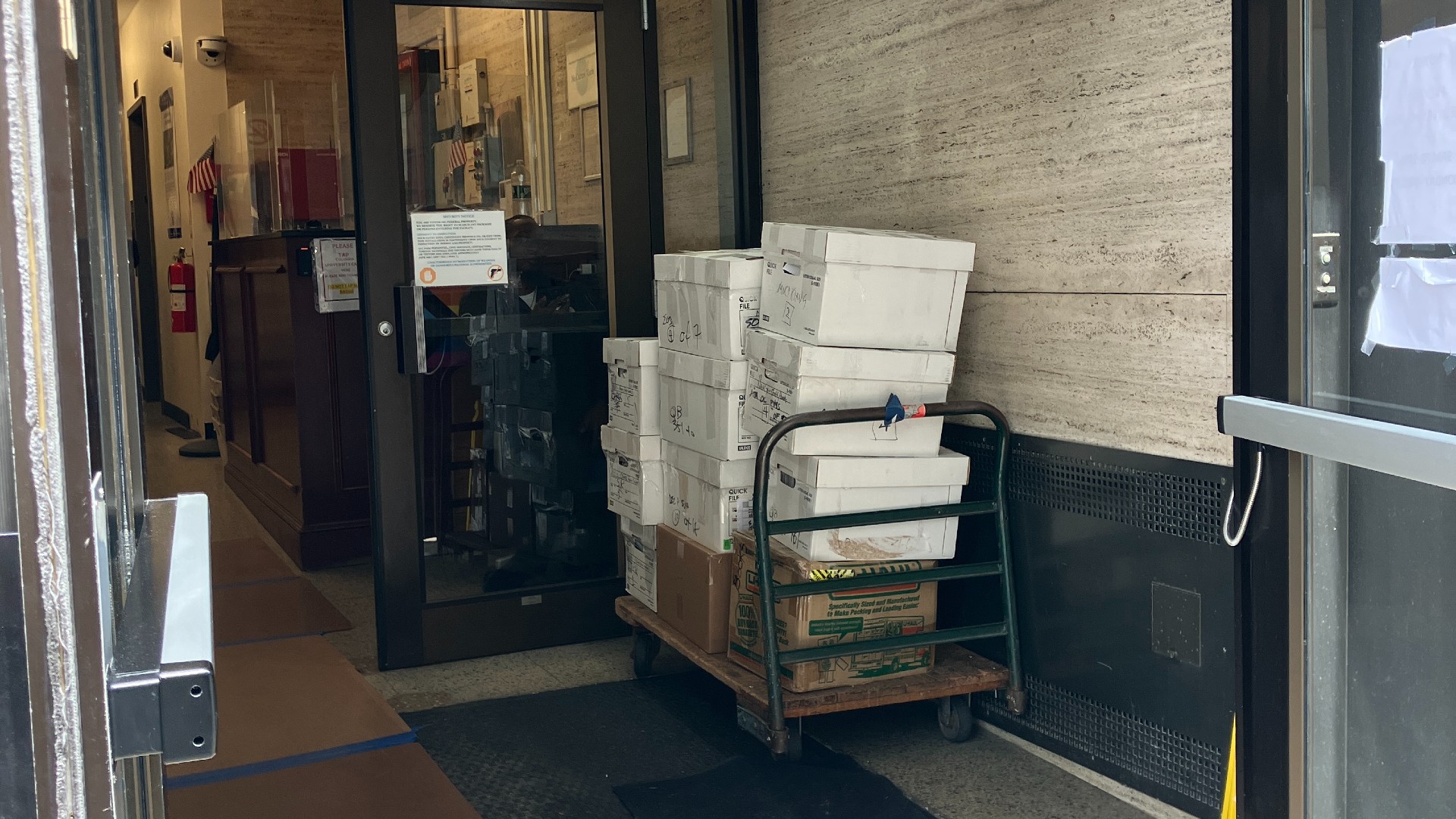 stacks of white boxes on a cart sit inside the doorway of a building