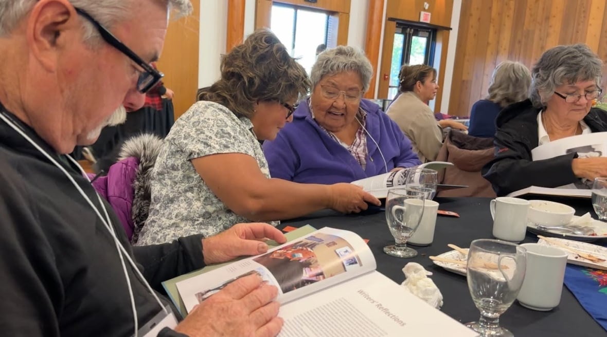People seated around tables all looking through copies of the book. 