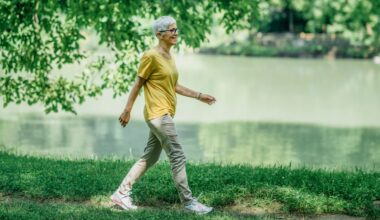 older woman walking on grass with a body of water behind her