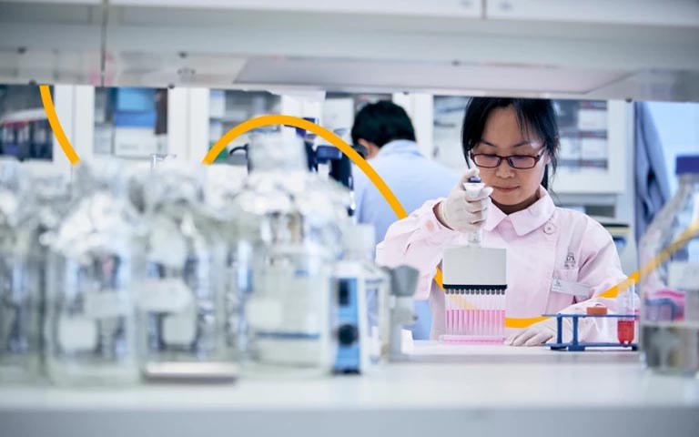 Wang Lin from Novo Nordisk China in a lab, wearing glasses and gloves, using a multi-channel pipette.