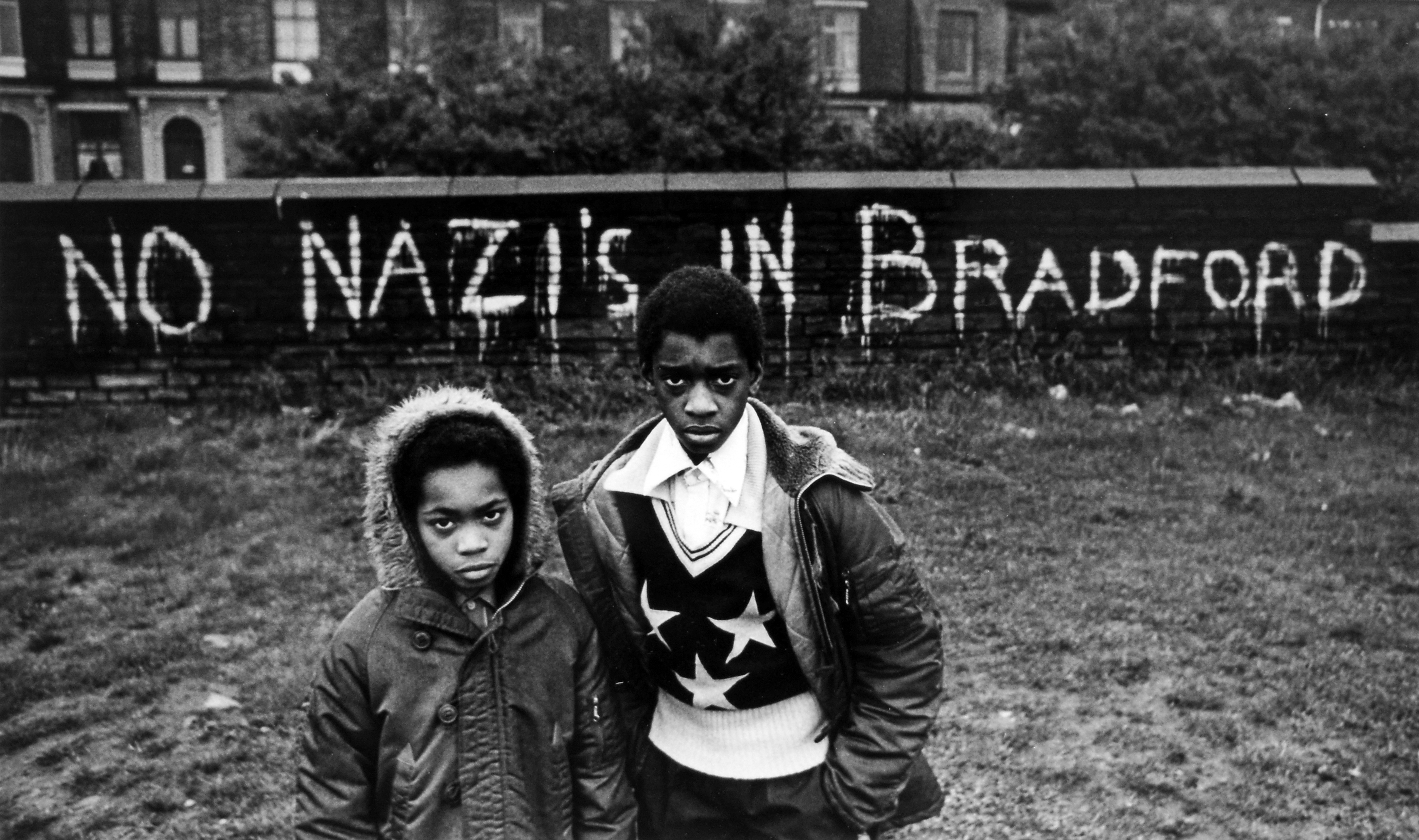 Two boys stand in front of a wall with "NO NAZI'S IN BRADFORD" painted on it.
