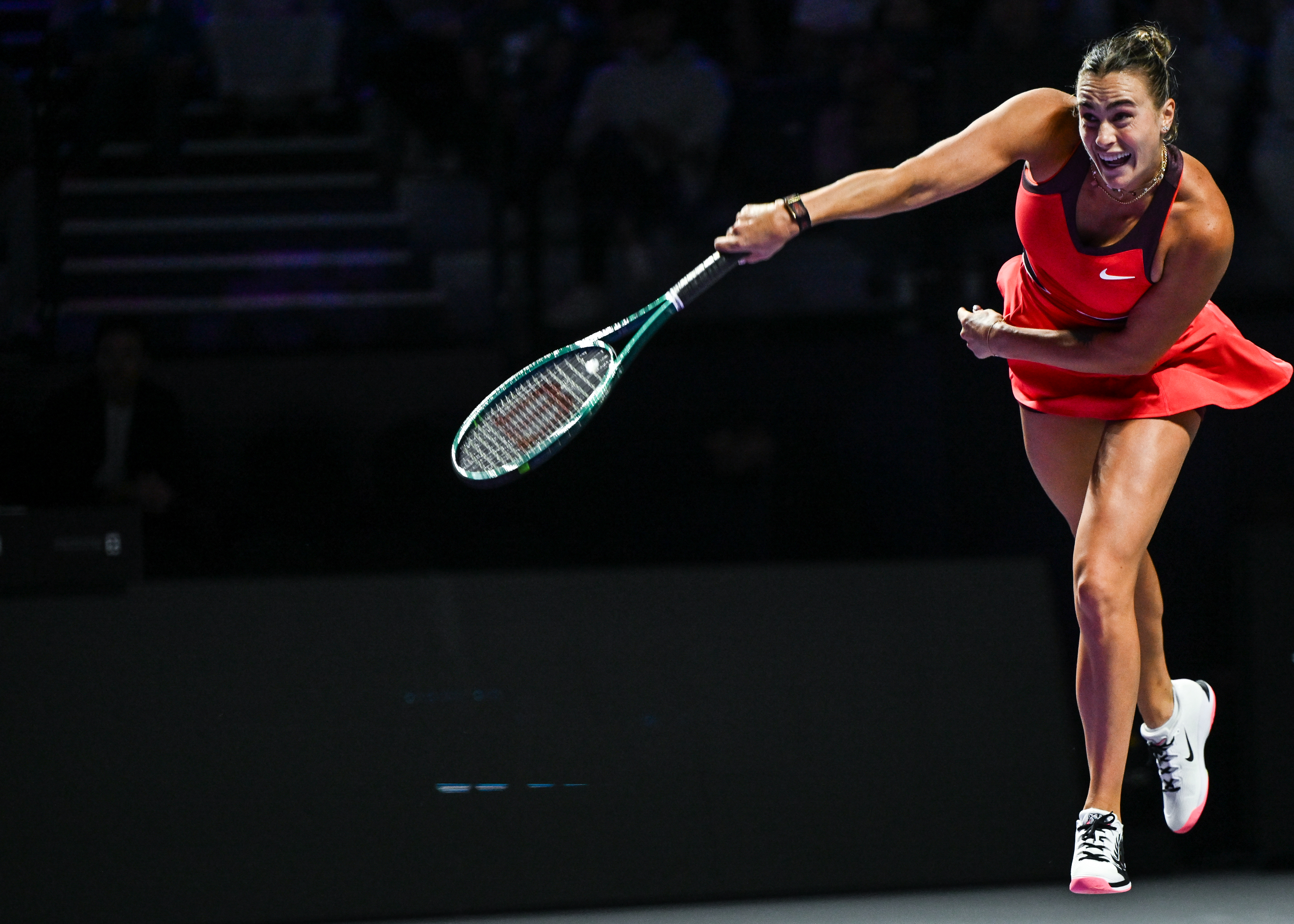 Aryna Sabalenka playing tennis, striking the ball during a group-stage match.